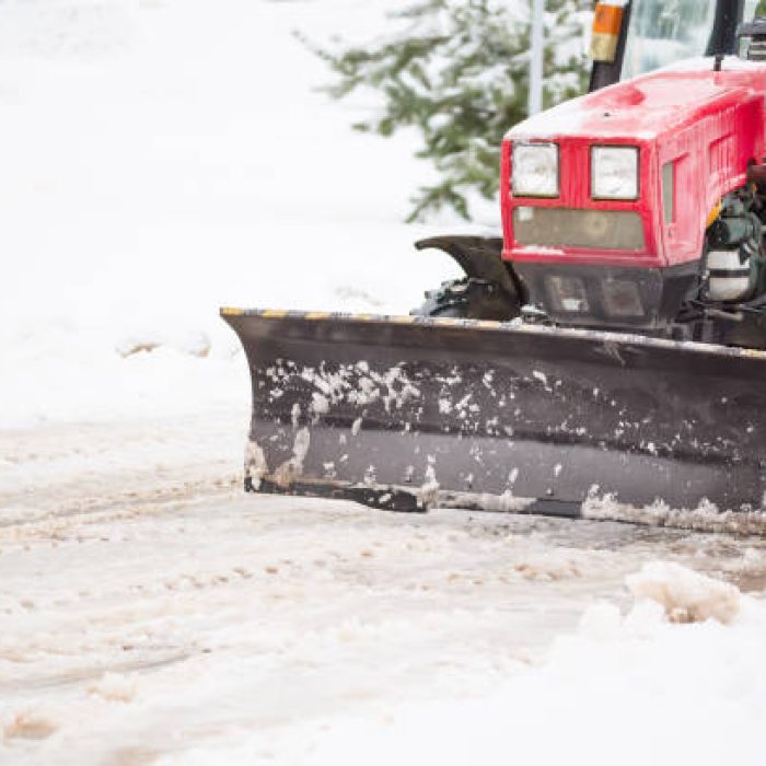 Red tractor cleaning the streets of large amounts of snow in city after snowfall. Winter time concept